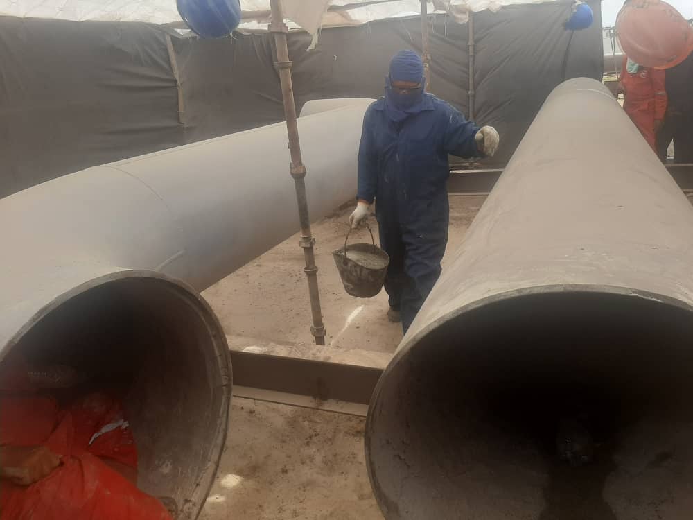Operario aplicando sandblasting a tubería